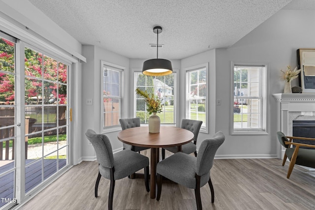 4812 Morecambe Way, Apex, NC 27539 - dining area featuring light wood-type flooring, a textured ceiling, and a fireplace
