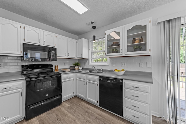 4812 Morecambe Way, Apex, NC 27539 - kitchen with black appliances, light wood-style flooring, white cabinets, a textured ceiling, and decorative backsplash