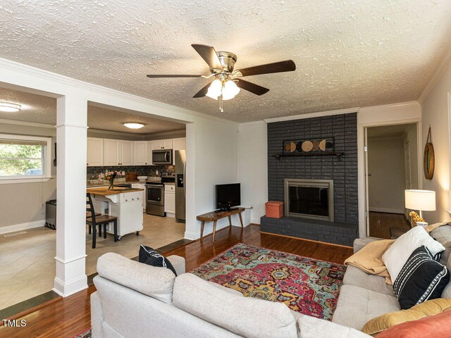 1831 Washington Dr, Hillsborough, NC 27278 - living room with a textured ceiling, ceiling fan, wood finished floors, crown molding, and a fireplace