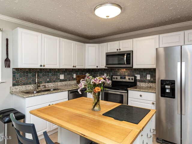 1831 Washington Dr, Hillsborough, NC 27278 - kitchen with appliances with stainless steel finishes, white cabinetry, tasteful backsplash, crown molding, and a textured ceiling