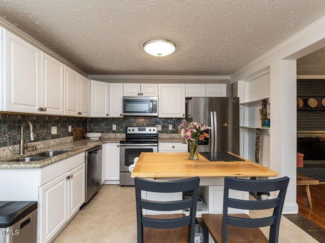 1831 Washington Dr, Hillsborough, NC 27278 - kitchen with appliances with stainless steel finishes, white cabinets, crown molding, a textured ceiling, and decorative backsplash