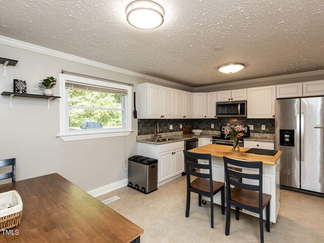 1831 Washington Dr, Hillsborough, NC 27278 - kitchen featuring appliances with stainless steel finishes, crown molding, white cabinets, backsplash, and a textured ceiling