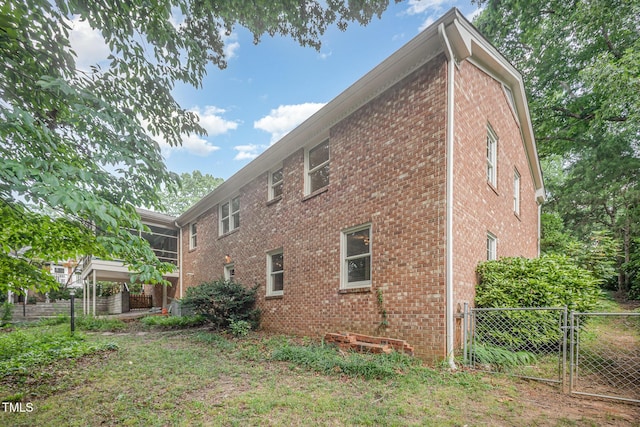 2425 Wentworth St, Raleigh, NC 27612 - view of side of home featuring brick siding, a gate, and a sunroom