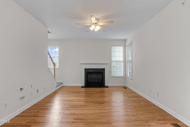 1401 Patterson Grove Rd, Apex, NC 27502 - unfurnished living room with a ceiling fan, a fireplace with flush hearth, light wood-style floors, and stairs