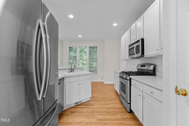 1401 Patterson Grove Rd, Apex, NC 27502 - kitchen featuring stainless steel appliances, light wood finished floors, light countertops, recessed lighting, and white cabinetry