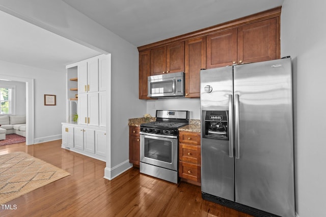 1116 E Martin St, Raleigh, NC 27610 - kitchen featuring appliances with stainless steel finishes, dark wood-style flooring, stone countertops, and brown cabinets