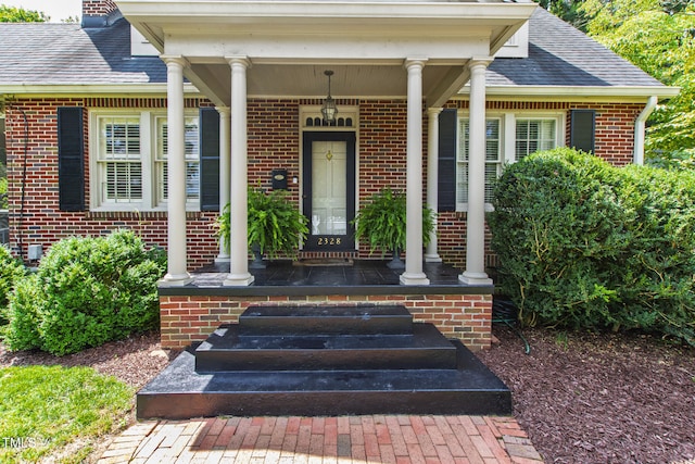 2328 Byrd St, Raleigh, NC 27608 - doorway to property featuring a porch, brick siding, and roof with shingles