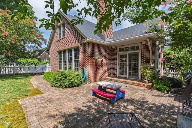 2328 Byrd St, Raleigh, NC 27608 - rear view of house with a patio area, roof with shingles, brick siding, and a chimney