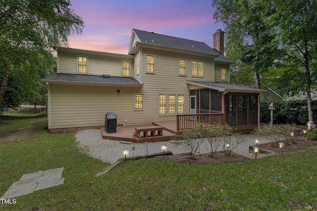 102 Glenmore Rd, Cary, NC 27519 - back of property at dusk featuring a sunroom, a chimney, a wooden deck, and a lawn