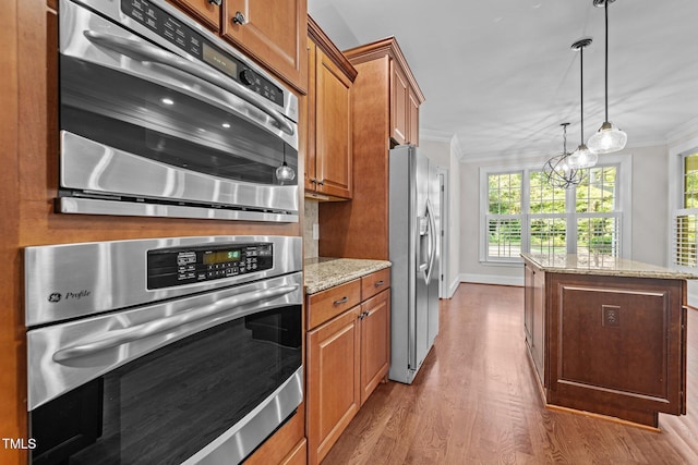 3005 Canopy Woods Dr, Apex, NC 27539 - kitchen featuring stainless steel appliances, crown molding, wood finished floors, brown cabinets, and a kitchen island