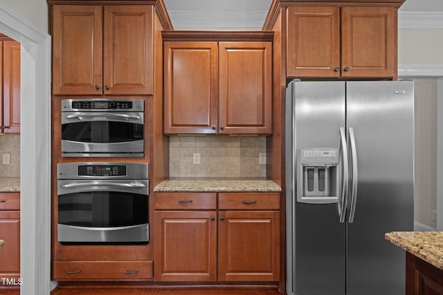 3005 Canopy Woods Dr, Apex, NC 27539 - kitchen with stainless steel appliances, crown molding, tasteful backsplash, light stone countertops, and brown cabinetry