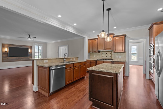 3005 Canopy Woods Dr, Apex, NC 27539 - kitchen featuring appliances with stainless steel finishes, a center island with sink, healthy amount of natural light, crown molding, and brown cabinets