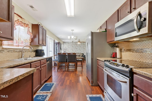 4017 Rothfield Ln, Raleigh, NC 27616 - kitchen featuring stainless steel appliances, a chandelier, dark wood finished floors, and backsplash