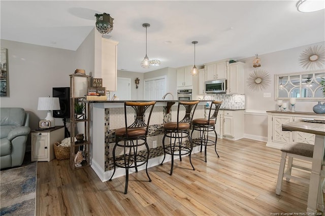 72 Orchard Falls Dr, Spring Lake, NC 28390 - kitchen with stainless steel appliances, light wood finished floors, a kitchen bar, and a peninsula