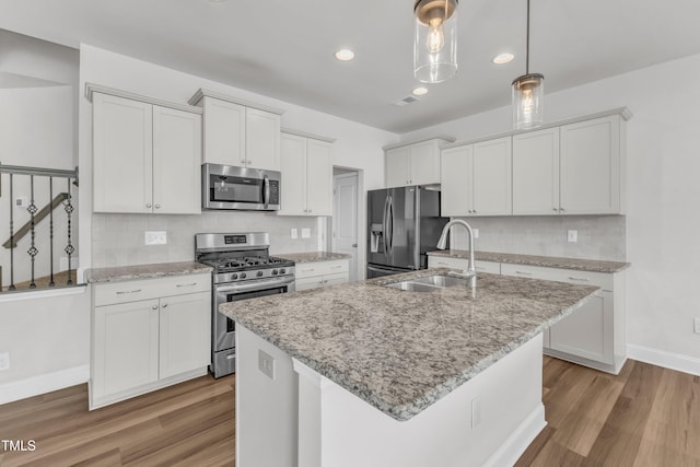 1126 Apogee Dr, Durham, NC 27713 - kitchen with appliances with stainless steel finishes, light wood-style floors, decorative backsplash, white cabinetry, and pendant lighting