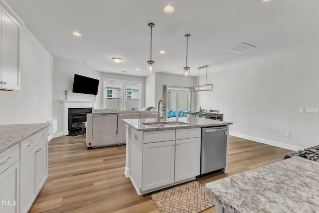 1126 Apogee Dr, Durham, NC 27713 - kitchen featuring stainless steel dishwasher, light wood finished floors, a fireplace with flush hearth, white cabinets, and recessed lighting