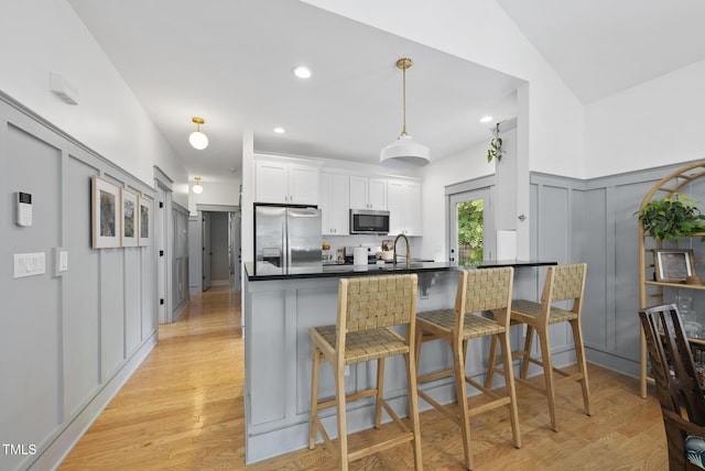 1010 S Person St, Raleigh, NC 27601 - kitchen with appliances with stainless steel finishes, dark countertops, a breakfast bar area, white cabinetry, and light wood finished floors