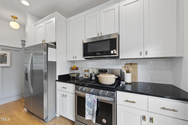 1010 S Person St, Raleigh, NC 27601 - kitchen with appliances with stainless steel finishes, white cabinetry, light wood finished floors, dark stone counters, and tasteful backsplash