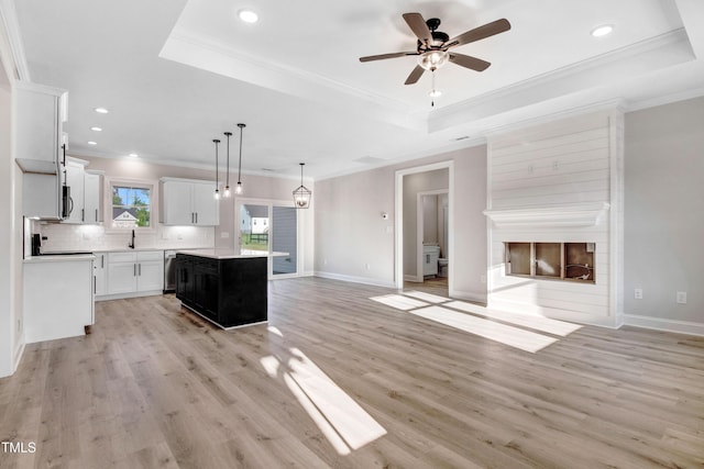 134 Cherrybirch Ln, Zebulon, NC 27597 - kitchen with open floor plan, a tray ceiling, a kitchen island, a fireplace, and decorative backsplash