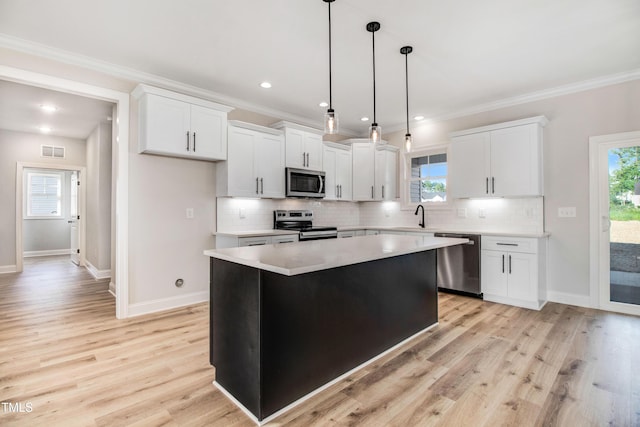 134 Cherrybirch Ln, Zebulon, NC 27597 - kitchen with stainless steel appliances, a kitchen island, decorative backsplash, ornamental molding, and white cabinetry