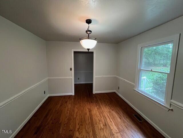 2856 Nutbush Rd, Henderson, NC 27537 - unfurnished dining area with dark wood-style flooring and baseboards