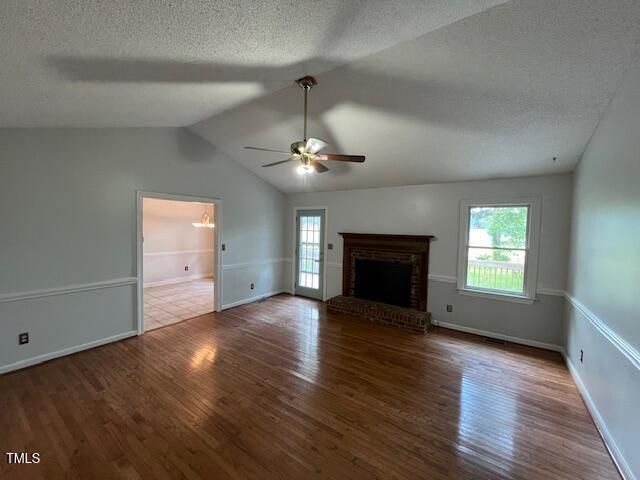 2856 Nutbush Rd, Henderson, NC 27537 - unfurnished living room with healthy amount of natural light, wood finished floors, a ceiling fan, a textured ceiling, and vaulted ceiling