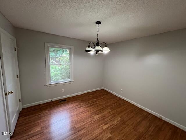 2856 Nutbush Rd, Henderson, NC 27537 - empty room with wood finished floors, a textured ceiling, and a chandelier