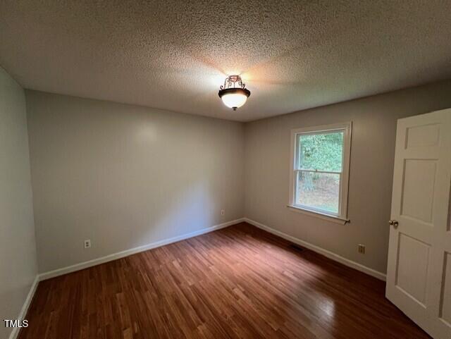 2856 Nutbush Rd, Henderson, NC 27537 - spare room with dark wood-style flooring and a textured ceiling