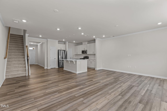 5721 Woodlawn Dr, Durham, NC 27703 - unfurnished living room with recessed lighting, wood finished floors, ornamental molding, and stairway