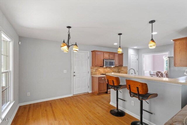 20 Allyson Ct, Youngsville, NC 27596 - kitchen with appliances with stainless steel finishes, a kitchen bar, light countertops, light wood finished floors, and recessed lighting