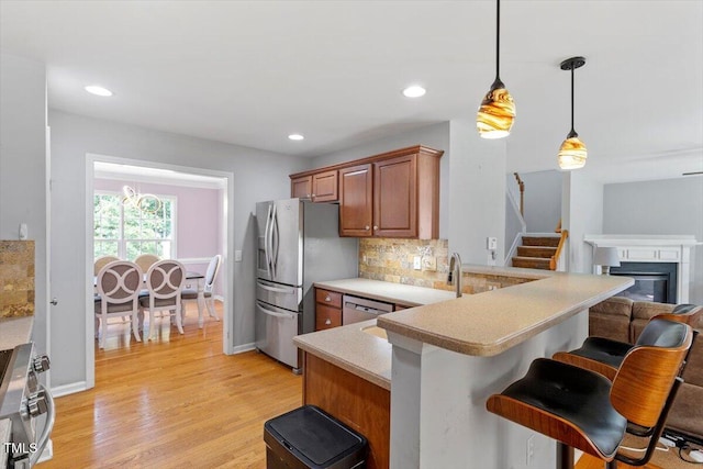 20 Allyson Ct, Youngsville, NC 27596 - kitchen with stainless steel appliances, a kitchen breakfast bar, brown cabinetry, light countertops, and decorative backsplash