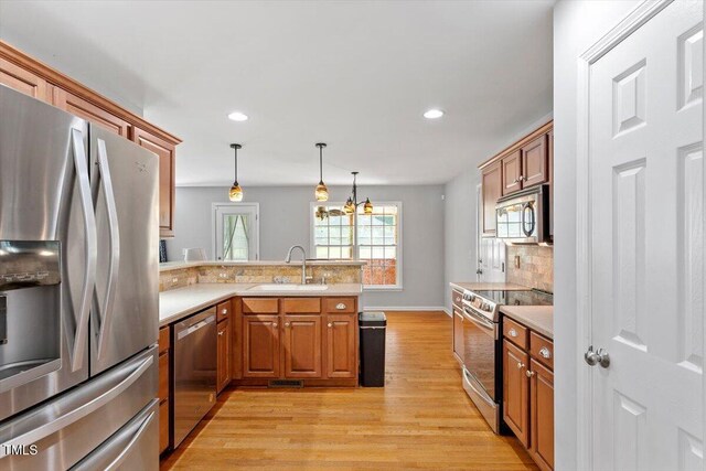 20 Allyson Ct, Youngsville, NC 27596 - kitchen with appliances with stainless steel finishes, a peninsula, brown cabinetry, light wood-type flooring, and tasteful backsplash