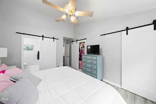 7645 Winners Edge St, Raleigh, NC 27617 - bedroom with a barn door, high vaulted ceiling, wood finished floors, connected bathroom, and a ceiling fan