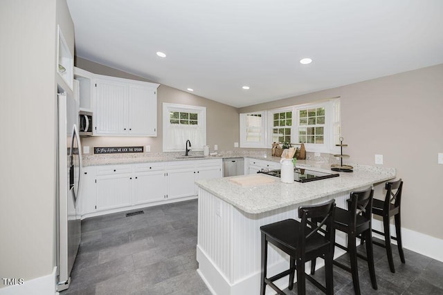 103 N Mckay Ave, Dunn, NC 28334 - kitchen featuring appliances with stainless steel finishes, a peninsula, white cabinetry, a breakfast bar area, and light stone counters