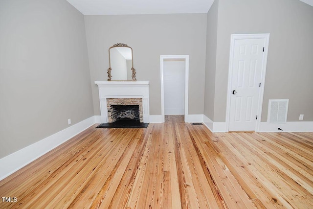 103 N Mckay Ave, Dunn, NC 28334 - unfurnished living room featuring light wood-type flooring and a stone fireplace
