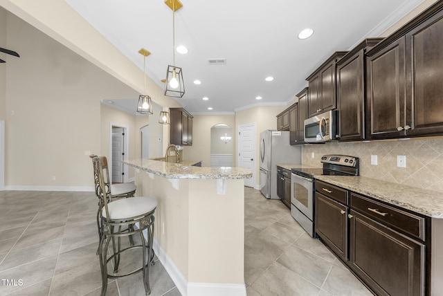 347 Country Mill Way, Fuquay Varina, NC 27526 - kitchen with appliances with stainless steel finishes, a breakfast bar, dark brown cabinetry, ornamental molding, and tasteful backsplash