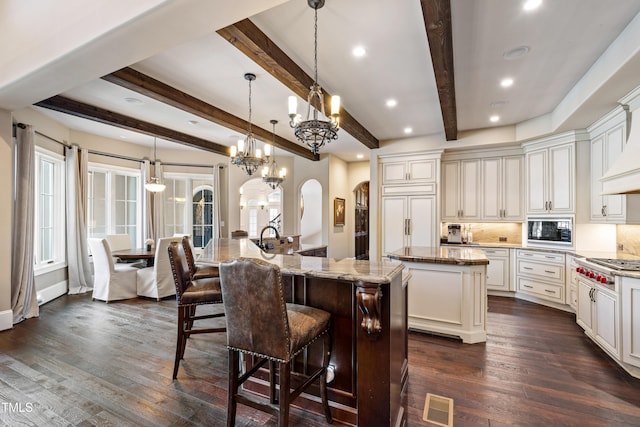 19 San Rimini Way, Durham, NC 27707 - kitchen featuring built in microwave, arched walkways, a large island, beamed ceiling, and decorative backsplash