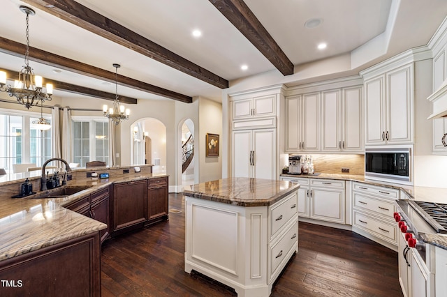 19 San Rimini Way, Durham, NC 27707 - kitchen with built in microwave, arched walkways, a chandelier, a spacious island, and light stone counters