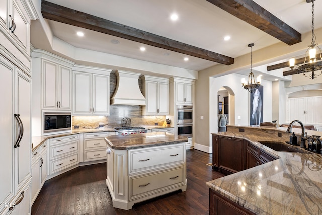 19 San Rimini Way, Durham, NC 27707 - kitchen with arched walkways, custom range hood, built in appliances, a center island, and backsplash