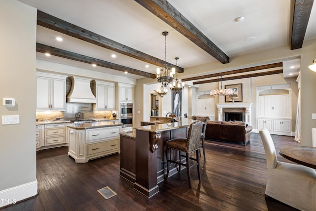 19 San Rimini Way, Durham, NC 27707 - kitchen with a spacious island, appliances with stainless steel finishes, cream cabinets, premium range hood, and a chandelier
