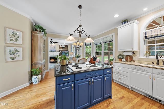 107 Ackworth Ct, Cary, NC 27519 - kitchen with white electric cooktop, ornamental molding, blue cabinets, white cabinetry, and a warm lit fireplace