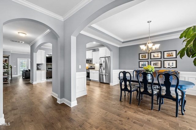 124 Moss Creek Pl, Fuquay Varina, NC 27526 - dining room with a chandelier, dark wood-style flooring, ornamental molding, arched walkways, and wainscoting