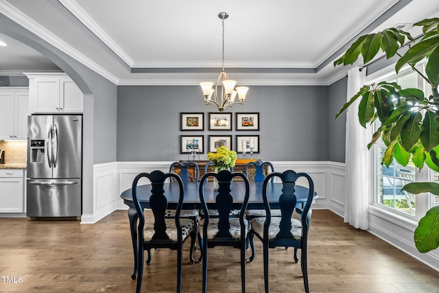 124 Moss Creek Pl, Fuquay Varina, NC 27526 - dining room featuring a chandelier, wainscoting, arched walkways, crown molding, and dark wood-style flooring