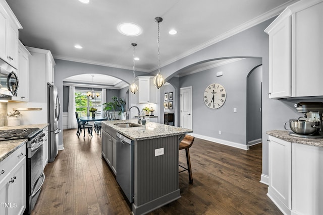 124 Moss Creek Pl, Fuquay Varina, NC 27526 - kitchen with appliances with stainless steel finishes, arched walkways, white cabinetry, a kitchen island with sink, and light stone countertops