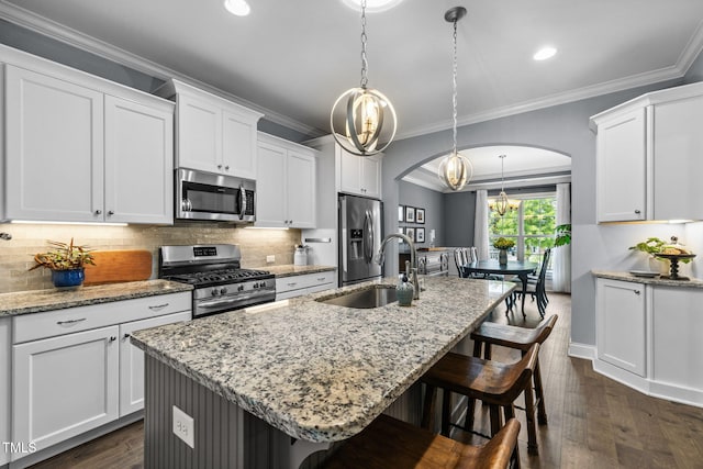 124 Moss Creek Pl, Fuquay Varina, NC 27526 - kitchen featuring appliances with stainless steel finishes, arched walkways, a kitchen bar, crown molding, and an island with sink