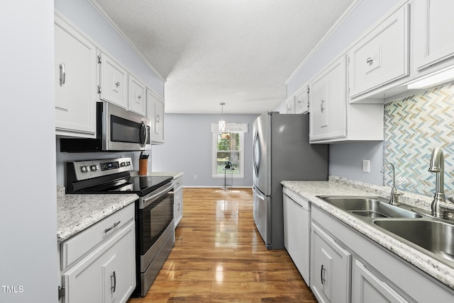 8613 Lobelia St, Raleigh, NC 27603 - kitchen with appliances with stainless steel finishes, white cabinets, light countertops, a textured ceiling, and wood finished floors