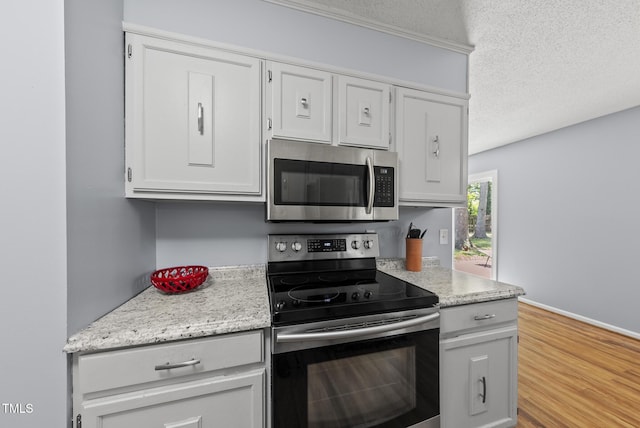 8613 Lobelia St, Raleigh, NC 27603 - kitchen with stainless steel appliances, white cabinets, a textured ceiling, and wood finished floors