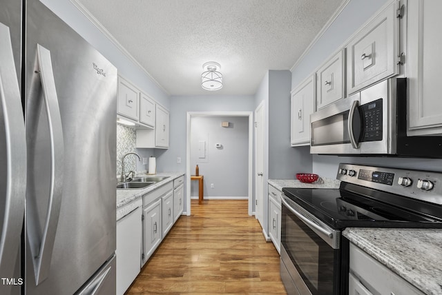 8613 Lobelia St, Raleigh, NC 27603 - kitchen with stainless steel appliances, light wood finished floors, a textured ceiling, and white cabinetry
