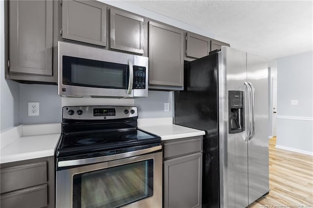1591 Hazelcrest Dr, Fayetteville, NC 28304 - kitchen featuring stainless steel appliances, gray cabinets, light countertops, light wood finished floors, and a textured ceiling
