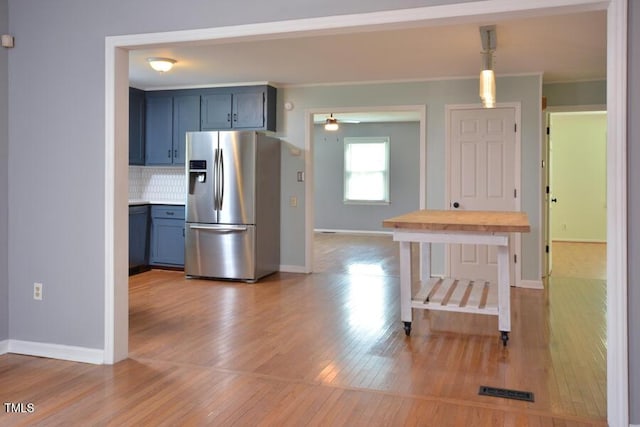 3300 Shaftsbury Drive St, Durham, NC 27704 - kitchen with stainless steel fridge, light wood-style floors, blue cabinets, crown molding, and decorative backsplash